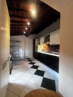 A kitchen with black and white checkered flooring, wooden ceiling beams, and modern cabinetry. - New Listing (Toscana)