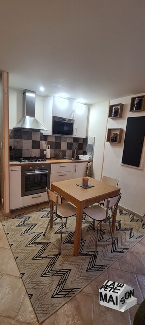Cozinha moderna com mesa de jantar, cadeiras e fogão.