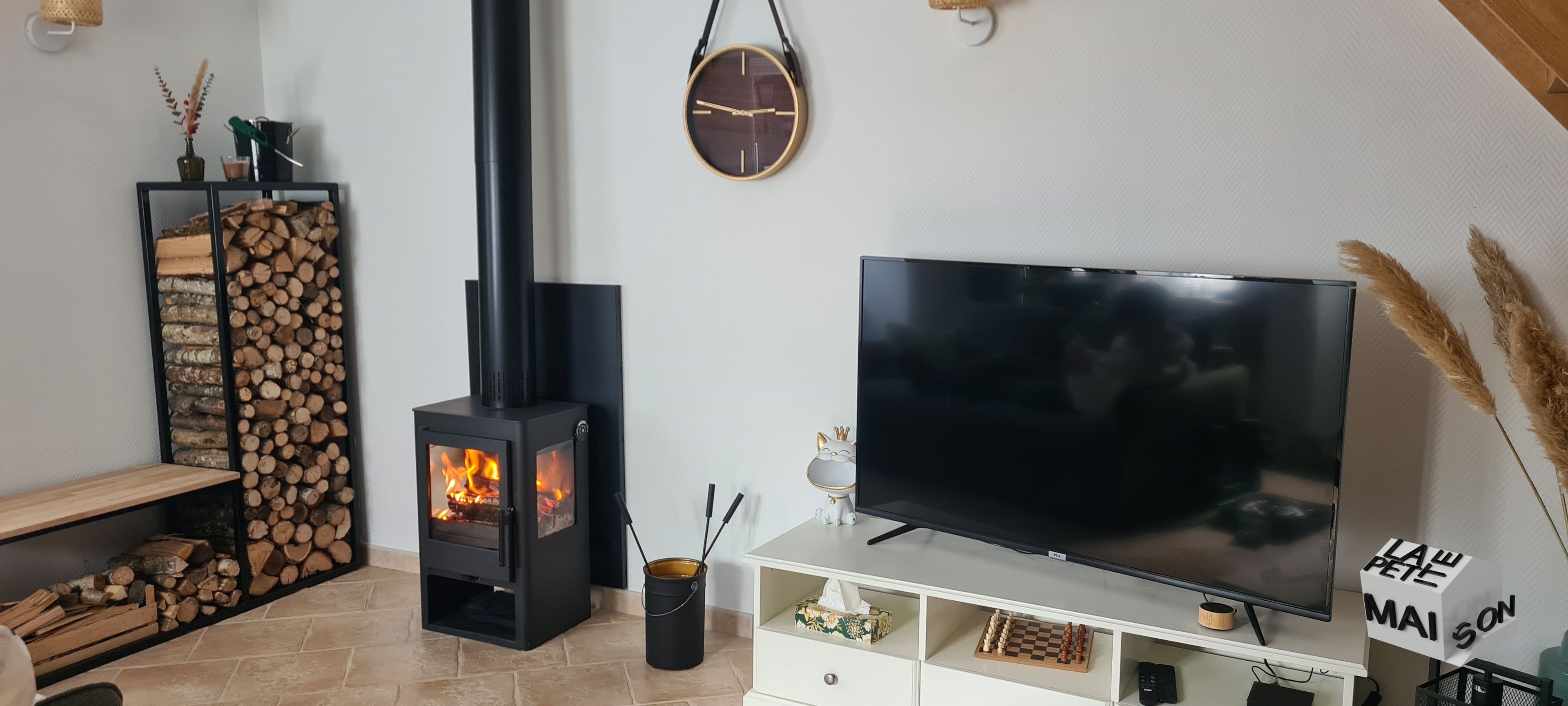 A living room with a TV, a fireplace, a clock, and a sign.