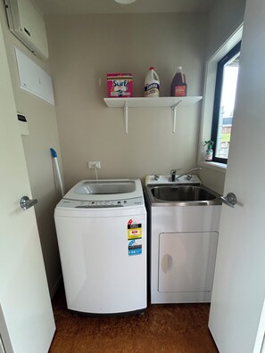 A compact kitchen with a washing machine, a sink, and a window. - Riley's Retreat. Family friendly house with sea view (Karikari Peninsula)