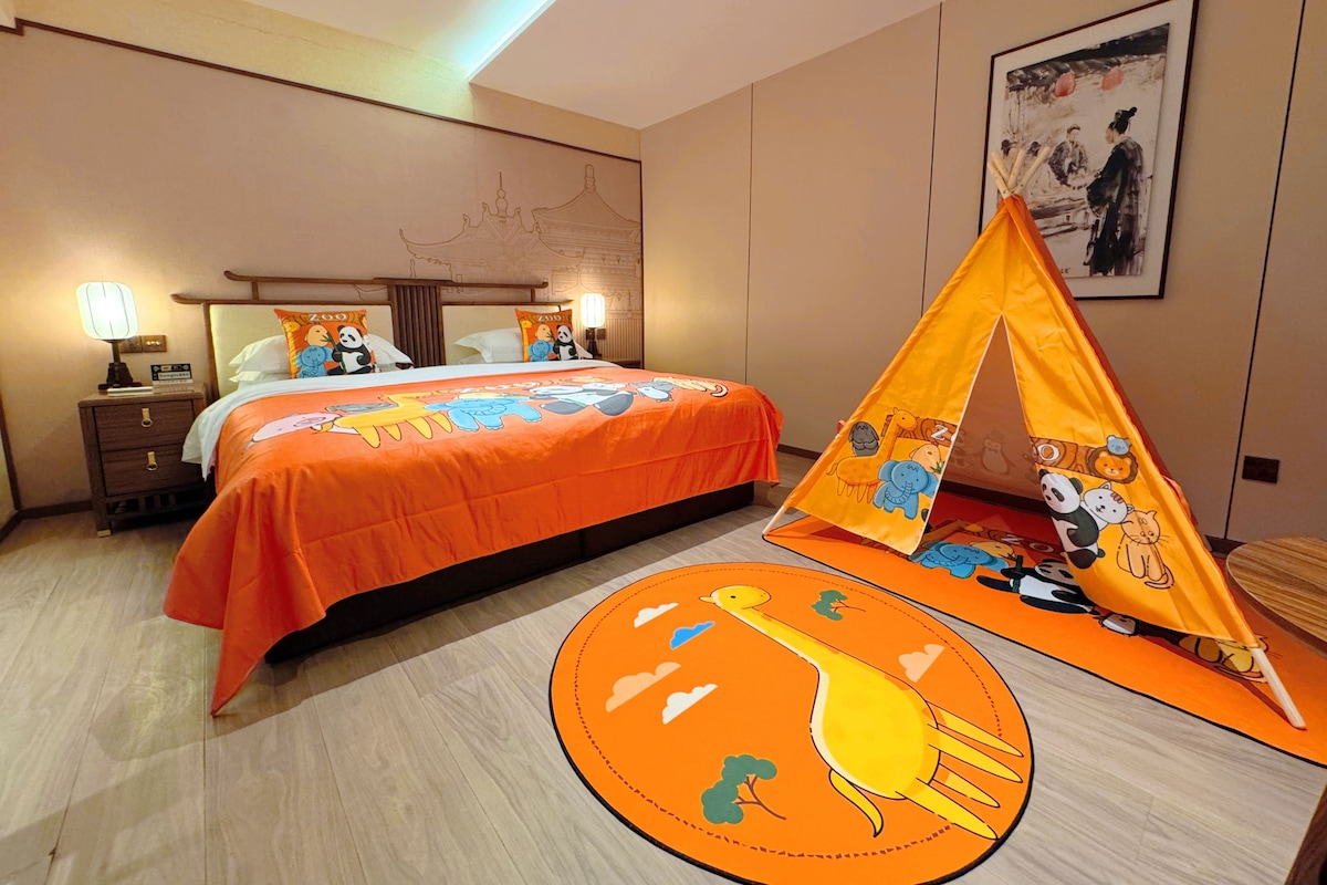 Une chambre d’hôtel avec un lit, une table de chevet, une lampe, un tableau au mur et une tente à motifs d’animaux.