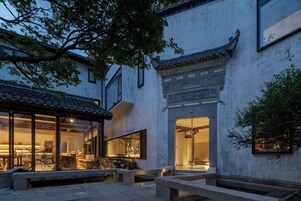 A traditional courtyard with a building featuring a tiled roof and a large open space with seating.