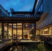 A traditional Japanese-style building with a koi pond, wooden furniture, and a view of the interior.
