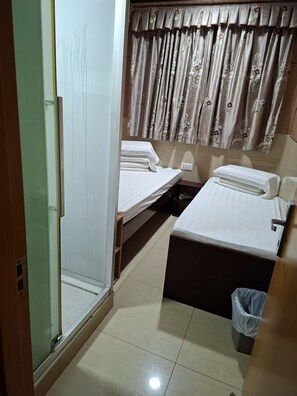 A hotel room with two beds, a shower area, and a curtain with floral patterns. - ME EASY HOSTEL (MongKok)