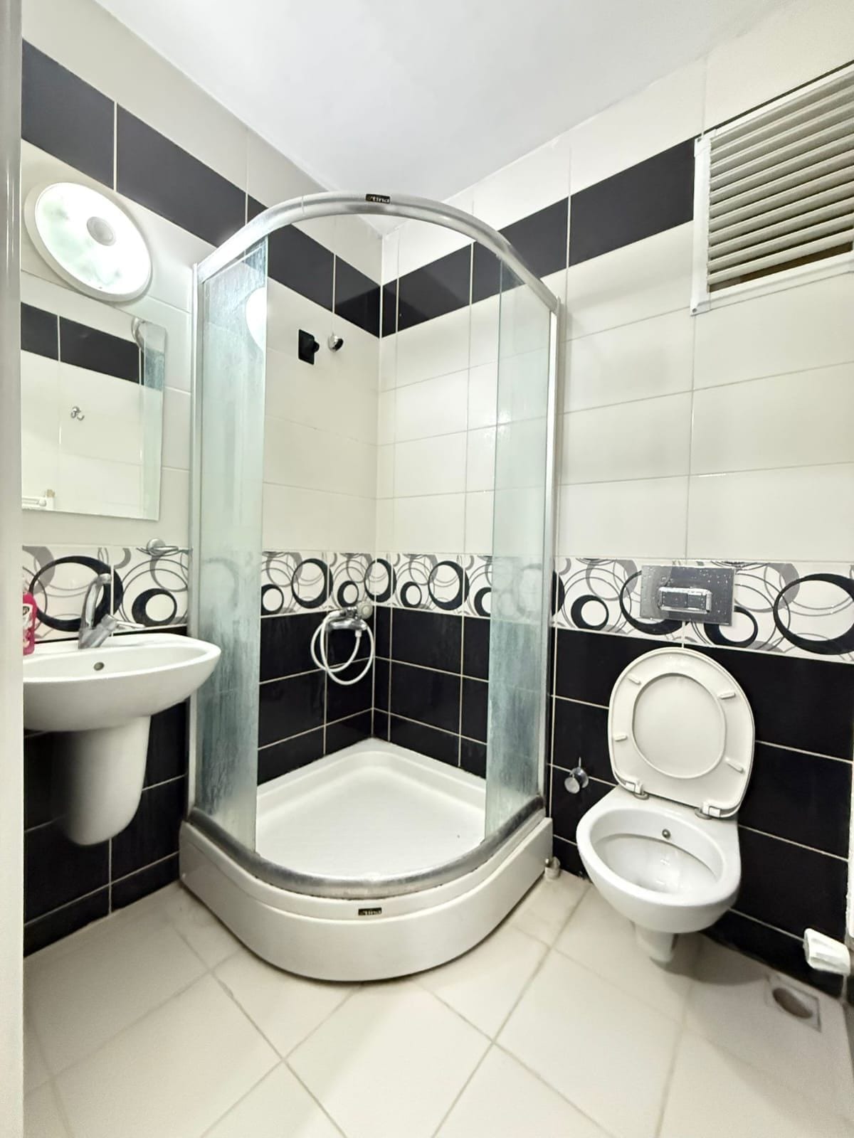 Un baño con ducha de vidrio, lavamanos y retrete.