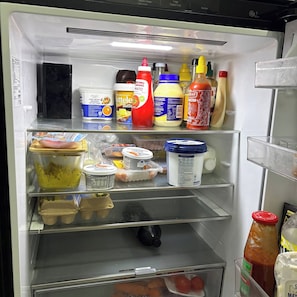 Ein gut sortierter Kühlschrank mit verschiedenen Lebensmitteln, darunter Gewürze, Milchprodukte und Eier.