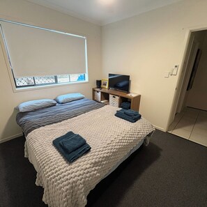 A bedroom with a bed, a television, a window, and a door. - Spacious, Stylish & Quite Greenslopes Apartment close to Hospitals & the City (Greenslopes)