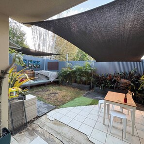 A patio area with a table and chairs, a covered seating area, and various plants. - Spacious, Stylish & Quite Greenslopes Apartment close to Hospitals & the City (Greenslopes)