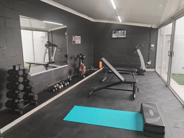 Een sportschool met trainingsapparatuur, een spiegel en een raam.