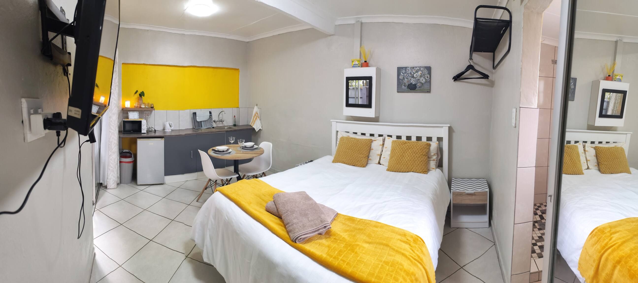 A hotel room with a bed, bedside table, and a small desk with a chair.
