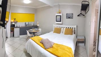 A hotel room with a bed, bedside table, and a small desk with a chair.