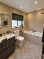 A modern bathroom with a bathtub, toilet, and sink.