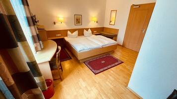 Een hotelkamer met een bed, nachtkastjes, een bureau en een stoel.
