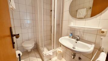 Ein Badezimmer mit Toilette, Dusche, Waschbecken und Spiegel.