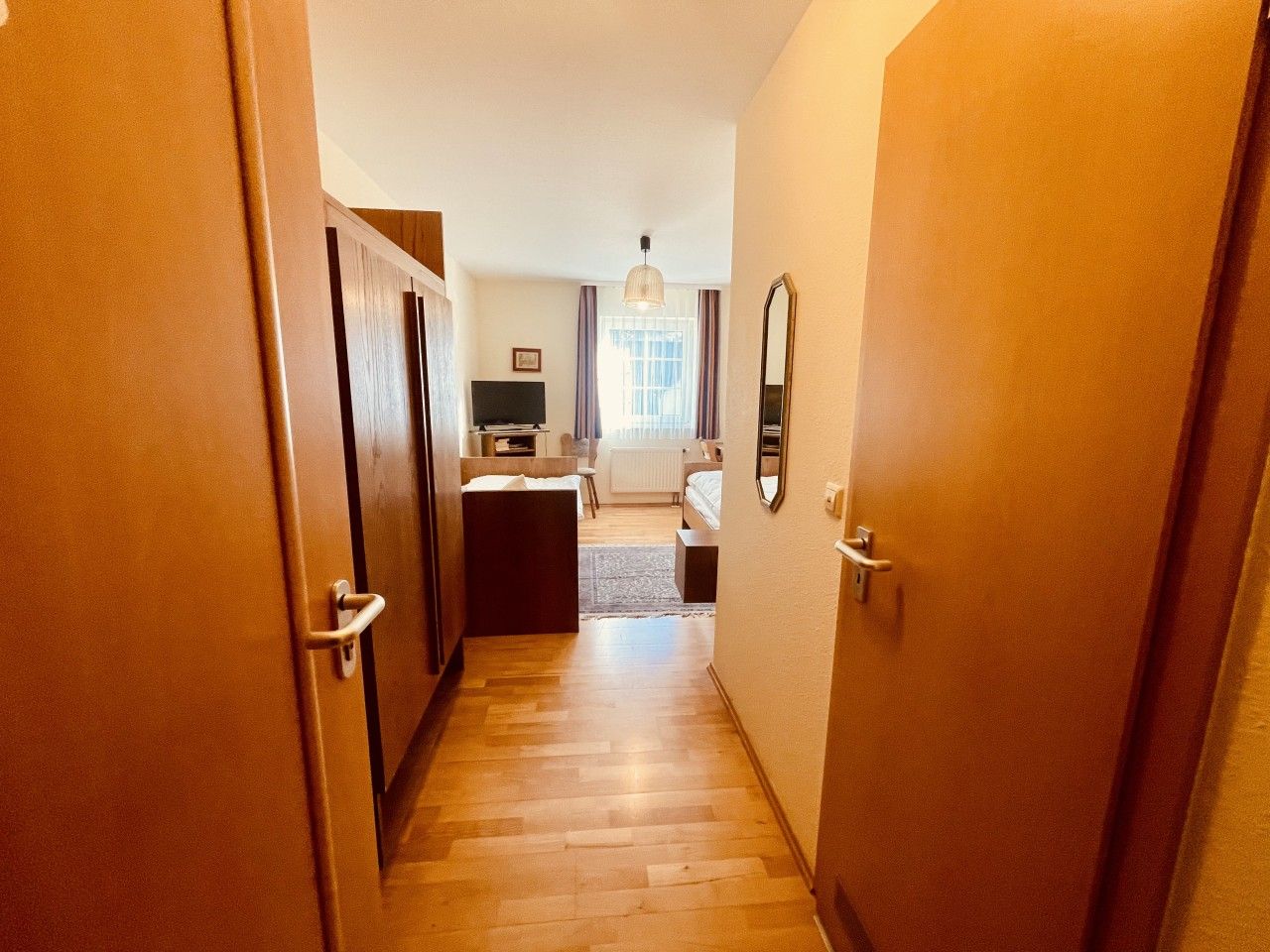 Ein Flur, der zu einem Schlafzimmer mit einem Bett, einem Schreibtisch und einem Stuhl führt.
