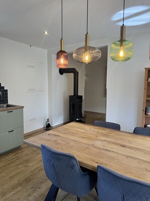 A modern dining area with a wooden table, blue upholstered chairs, and pendant lighting. - Holiday Apartment 'Burghof' with Shared Garden and Wi-Fi (Leibertingen)