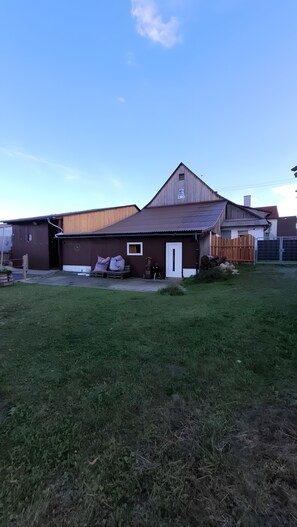 A single-story building with a brown roof and a white door, surrounded by a grassy yard. - Holiday Apartment 'Burghof' with Shared Garden and Wi-Fi (Leibertingen)