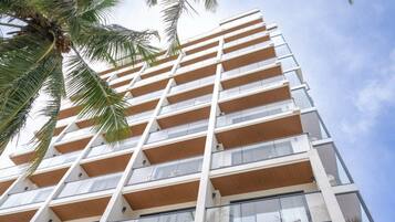 Un edificio de varios pisos con un diseño arquitectónico moderno, que presenta balcones con barandas de madera y ventanas amplias.