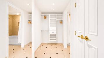A hallway with a walk-in closet, a shower area, and a door with a gold handle.