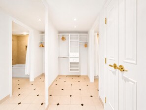 Ein Flur mit begehbarem Kleiderschrank, einer Duschkabine und einer Tür mit goldener Griff.