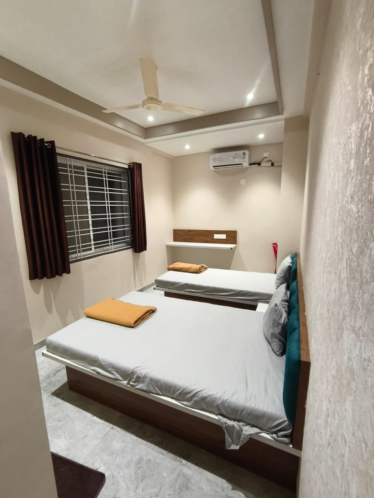 Una habitación de hotel con cama, aire acondicionado, ventana con cortinas y ventilador de techo.
