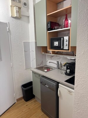 Een praktische keuken met een inbouwvaatwasser, koffiezetapparaat en een magnetron.