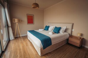 A hotel room with a large bed, bedside tables, a floor lamp, and a view through a glass door. - Stefanos Rock, Villa (Corfu)