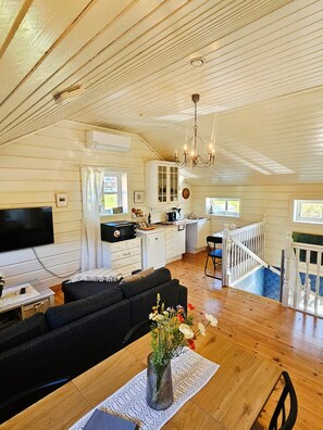 A spacious living area with a sofa, a dining table with a vase of flowers, and a kitchen with a chandelier.