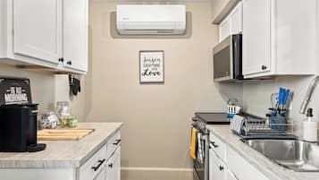 A modern kitchen with white cabinets, a microwave, an oven, and a coffee machine.