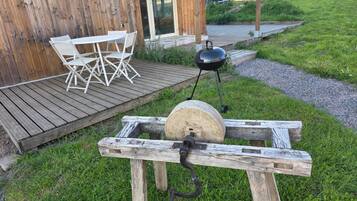 Un barbecue extérieur en bois, avec une table et des chaises à proximité.