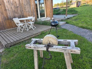 A wooden outdoor grill setup with a table and chairs nearby.