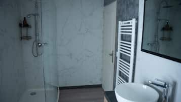 A modern bathroom with a glass shower enclosure, a white sink, and a marble wall.