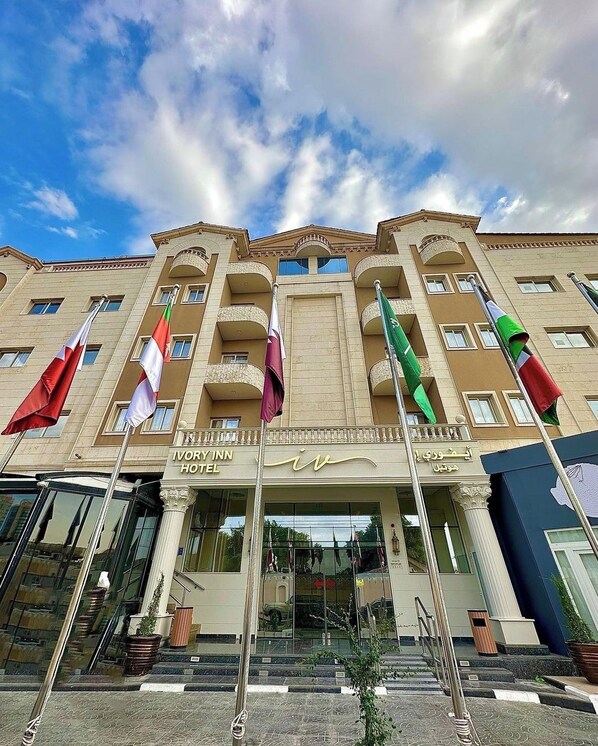 Un hôtel doté de nombreux balcons, d’une entrée en verre et de drapeaux.