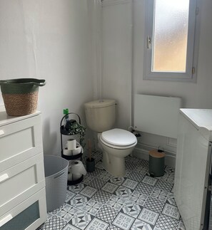 Ein kleines, kompaktes Badezimmer mit Toilette, Waschbecken und Fenster.