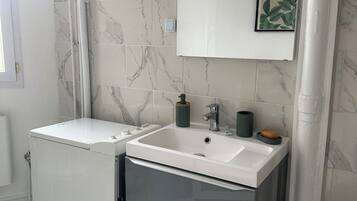 Casa de banho com lavatório branco, espelho e sanita.