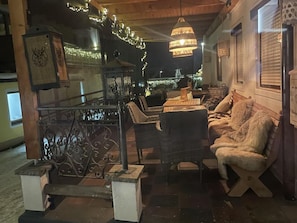 En utomhusplats med sittmöbler i rotting, en hängande lampa och en dekorativ lykta.