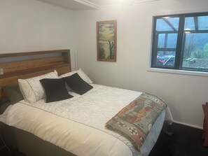 Een slaapkamer met een bed, een raam en een schilderij aan de muur.