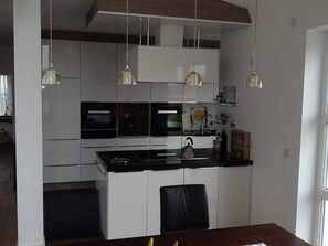 Eine moderne Küche mit weißen Schränken, einer schwarzen Arbeitsplatte und Pendelleuchten.