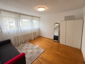 Une pièce avec un plancher en bois, un canapé, un miroir et une armoire.