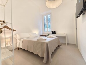 Et soveværelse med seng, sengebord, lampe og et vindue.