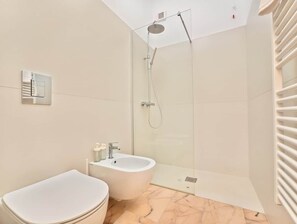 Et moderne badeværelse med bruser, bidet og toilet.