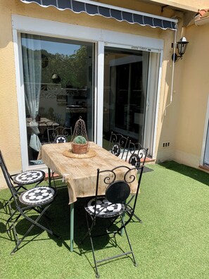 An outdoor patio with a table and chairs, a potted plant, and a sliding glass door. - New Listing (Le Barcarès)