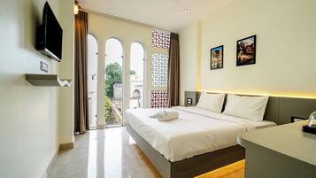 Una habitación de hotel moderna con una cama grande, un televisor de pantalla plana en la pared y un balcón con vista a la ciudad.