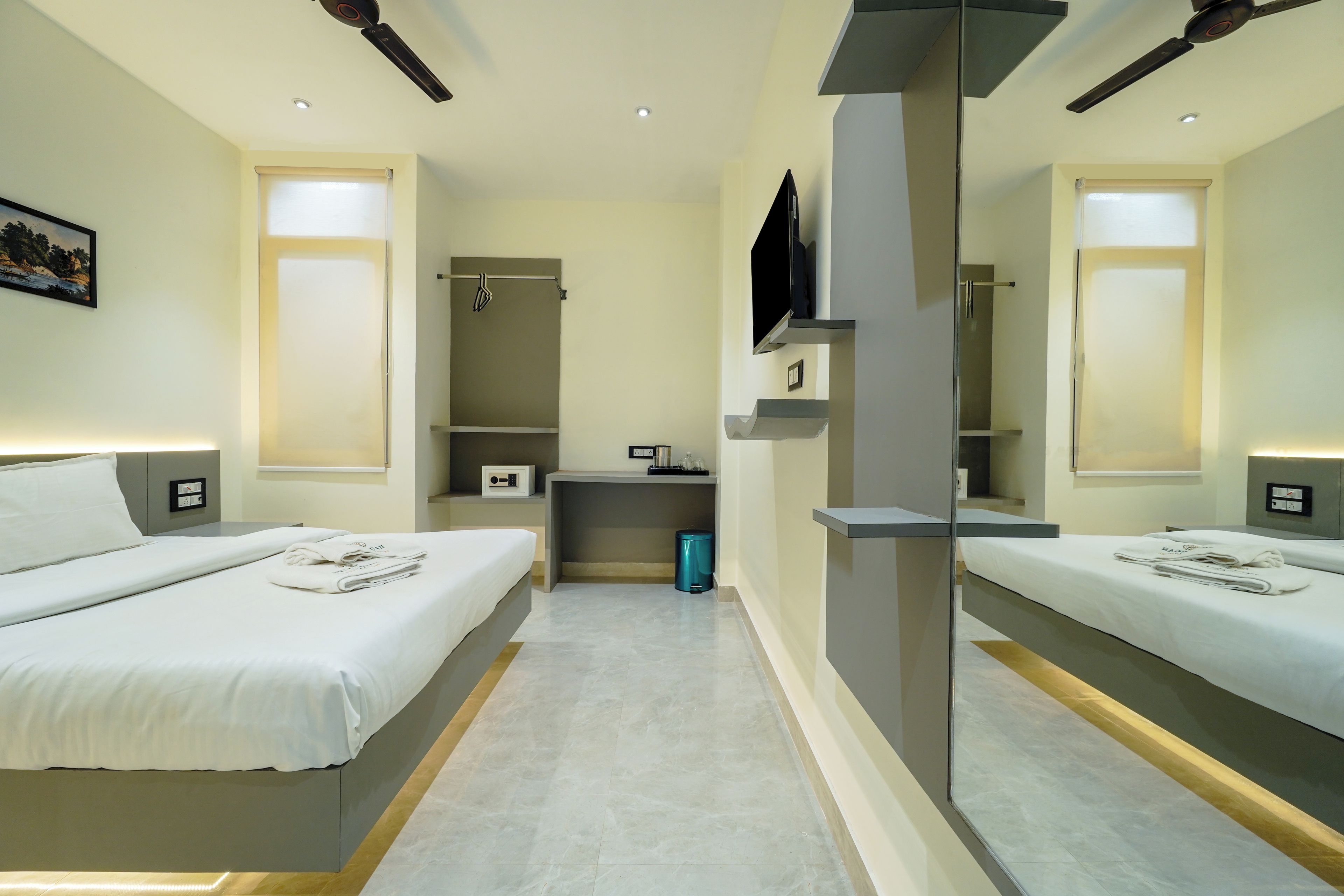 Una habitación de hotel con dos camas, televisión, escritorio y espejo.