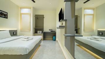 Una habitación de hotel con dos camas, televisión, escritorio y espejo.