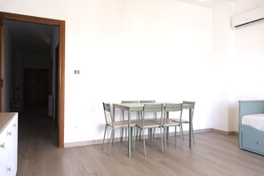 Une pièce comprenant une table et des chaises, un lit et un mur blanc.