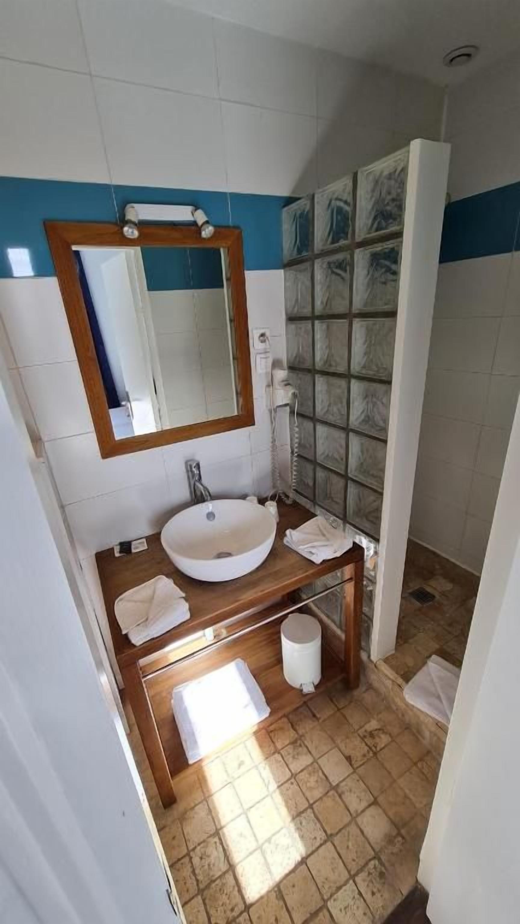 A bathroom with a sink, mirror, and shower.