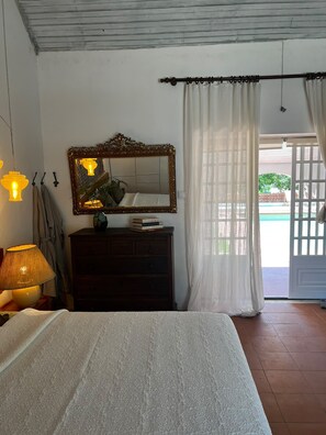 A bedroom with a bed, a dresser, a mirror, and a window with curtains. - Mil Flores Pool Villa · Quinta de Margoa (Fajarda)
