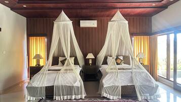 A double bed with a canopy, a nightstand with a lamp, and a large window with curtains.