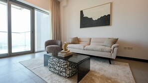 A modern living room with a sofa, a patterned ottoman, and a coffee table.